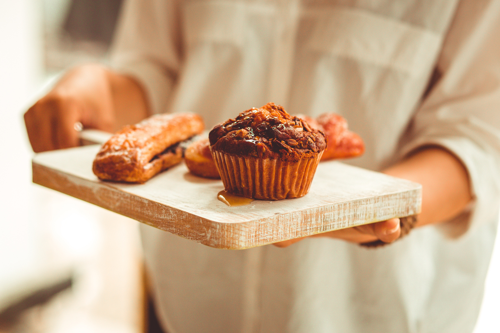 Person Serving Muffin On Wooden Tray